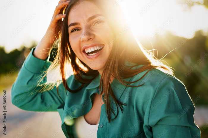 Young woman in green shirt smiling in a park